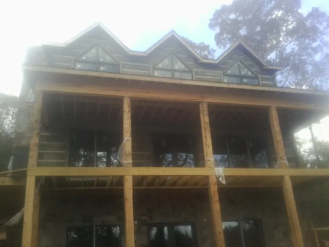 Dormers and porch framing on a large log home under construction — Roof Coating work by our crew in Halstad