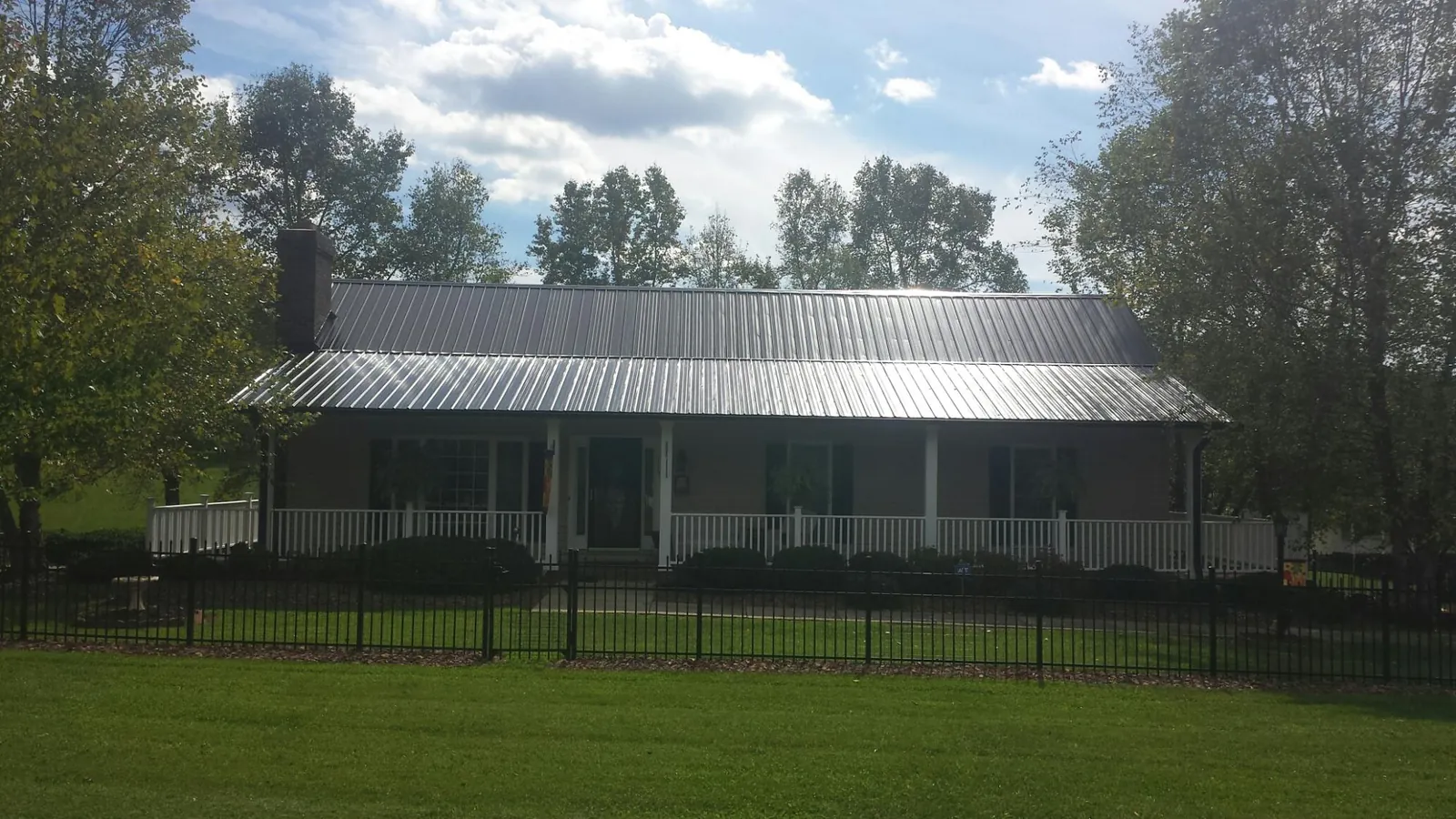 Gray metal roof on a brick ranch with a full width front porch — Gutter Guard Installation work by our crew in Halstad