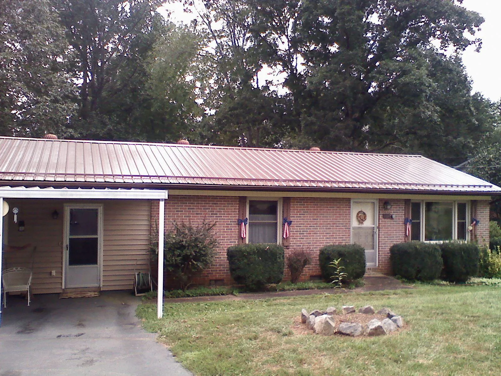 Bronze metal roof and carport on a brick ranch home — Roof Repair work by our crew in Halstad