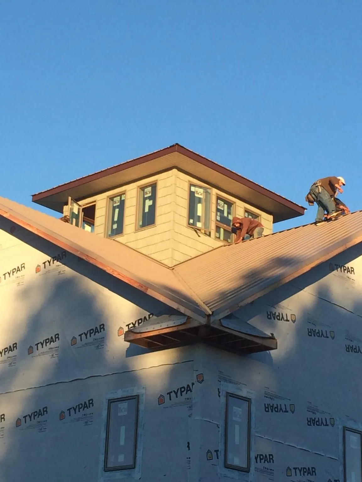 Roofers working around a rooftop cupola on a new metal roof at sunset — Roof Waterproofing in Halstad by Roofing Brothers